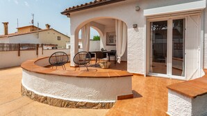 A patio with a curved stone bench, two chairs, and a table.