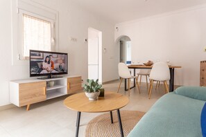 A modern living room with a TV, a dining table, chairs, and a sofa.