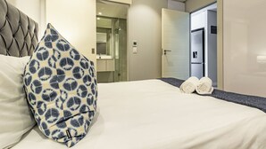 Une chambre d’hôtel avec un lit, un oreiller, une serviette, un miroir et une porte donnant sur la salle de bain.