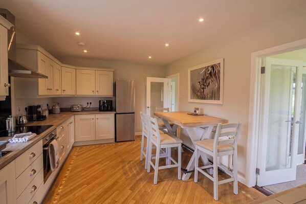 A modern kitchen with white cabinets, a wooden countertop, and a dining area with a table and chairs.