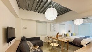 A modern, well-lit living space with a sofa, dining table, and a bed. - Arts Dobashi 3N (Hiroshima)