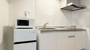 A compact kitchen with a microwave, sink, and stainless steel cabinets. - Arts Dobashi 3N (Hiroshima)