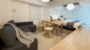 A modern, well-lit room with a sofa, dining table, and a bed. - Arts Dobashi 3N (Hiroshima)