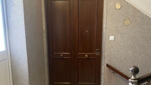Una puerta doble de madera con los números 1 y 2 encima, que da a una escalera de mármol con barandilla de metal.