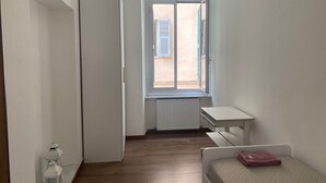 Una habitación pequeña y limpia con una cama, un escritorio y una ventana.