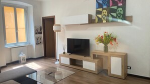 Una sala de estar moderna con un televisor de pantalla plana, una mesa de centro de vidrio y un mueble de madera para entretenimiento.