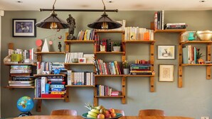 A dining area with a wooden table, chairs, a globe, and bookshelves filled with books and decorative items. - Stylish Family Home with Garden (Bristol)