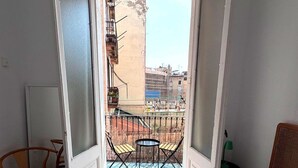 Habitación de hotel con cama, una silla y vistas a un balcón con mesa y sillas.