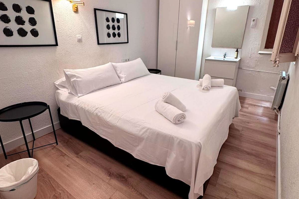A neatly arranged bedroom with a bed, bedside tables, a small table, and a wardrobe.