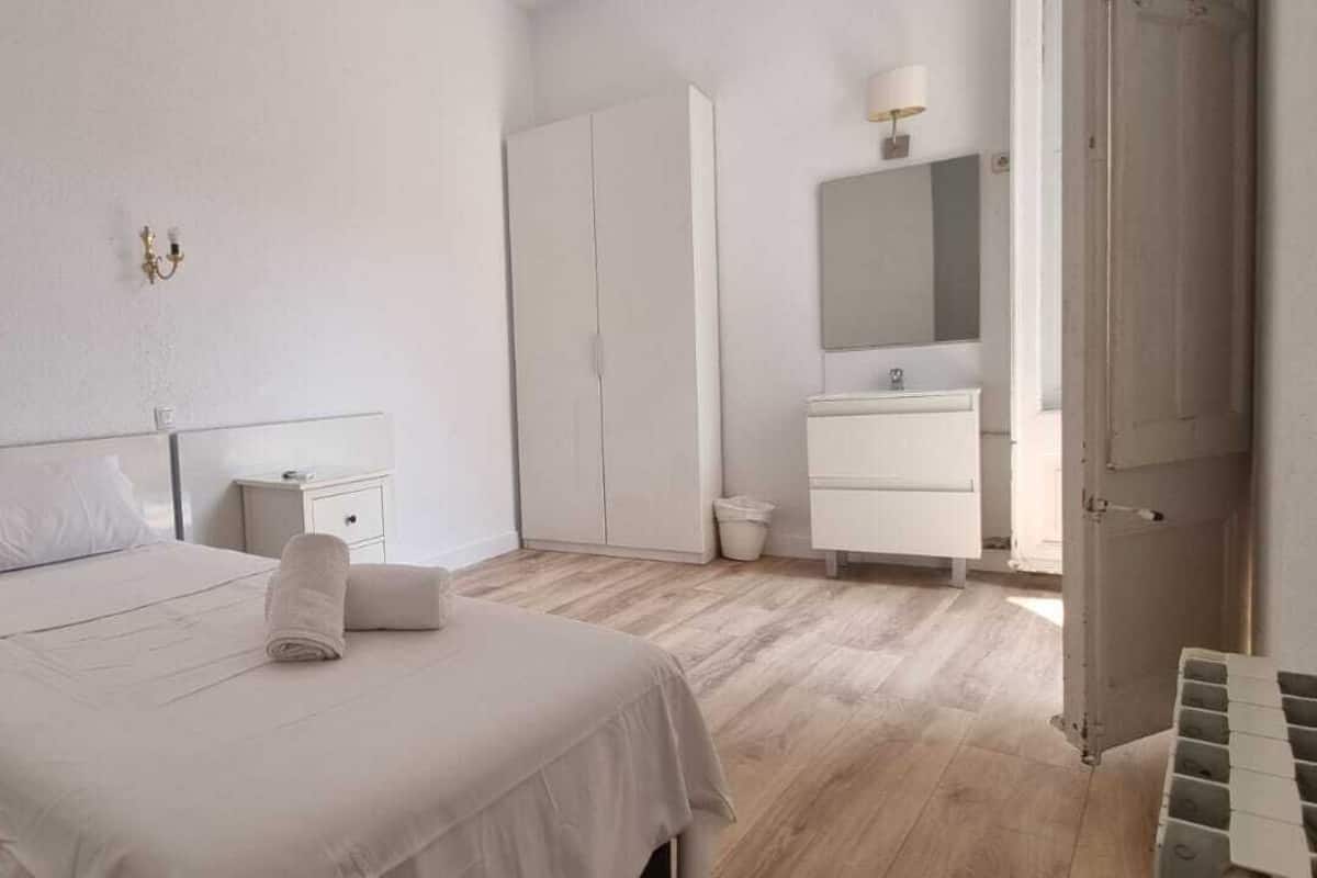 A bedroom with a bed, bedside tables, a wardrobe, a mirror, and a radiator.