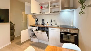 Una cocina compacta con horno empotrado, cafetera y lavabo.