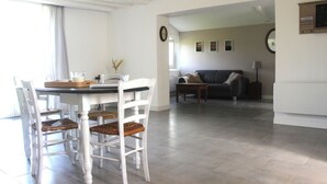 Ein Essbereich mit Tisch, Stühlen, einer Couch und einer Uhr an der Wand.