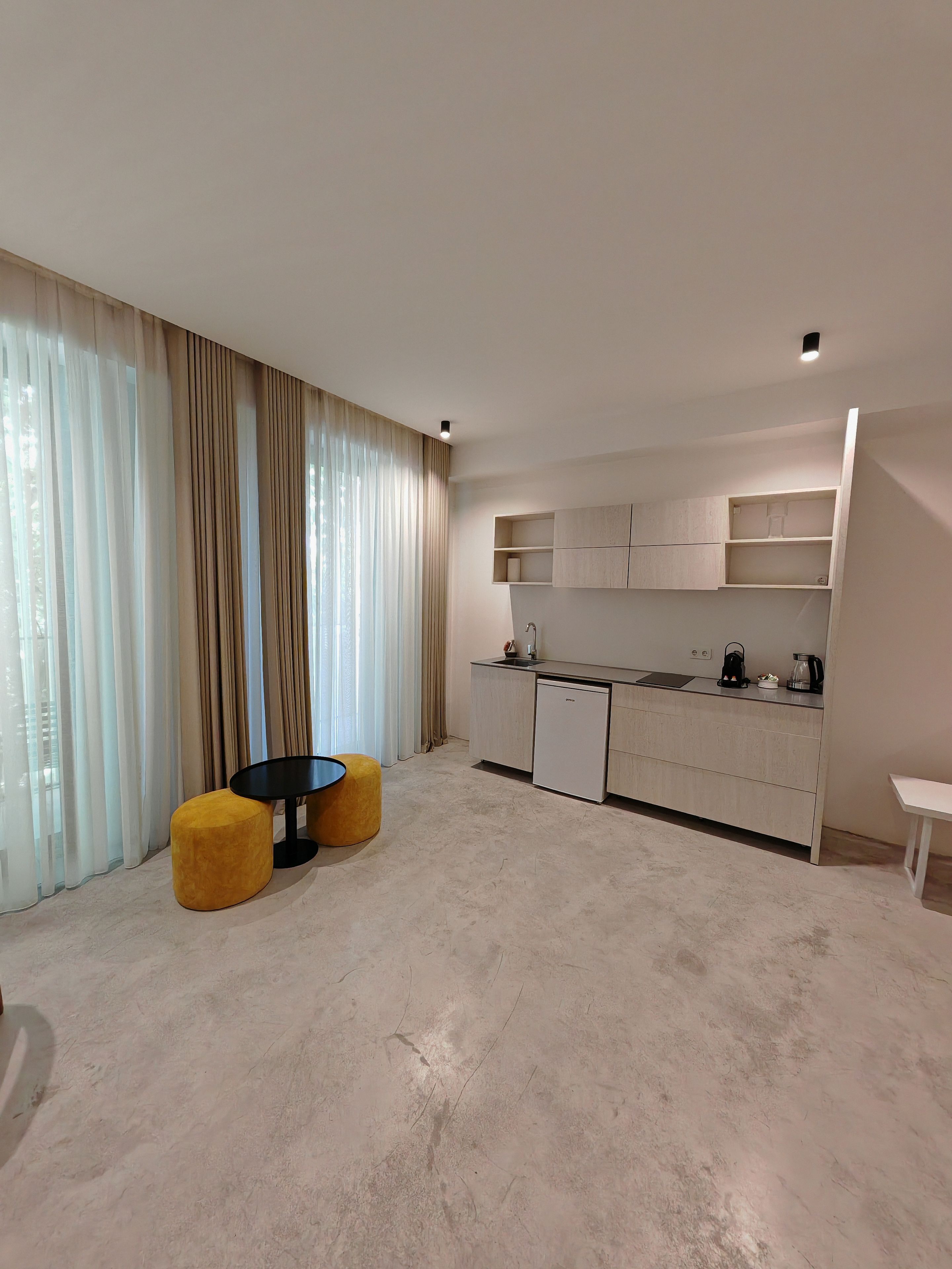 Una cocina moderna con lavavajillas incorporado, cafetera y un pequeño comedor con dos taburetes.