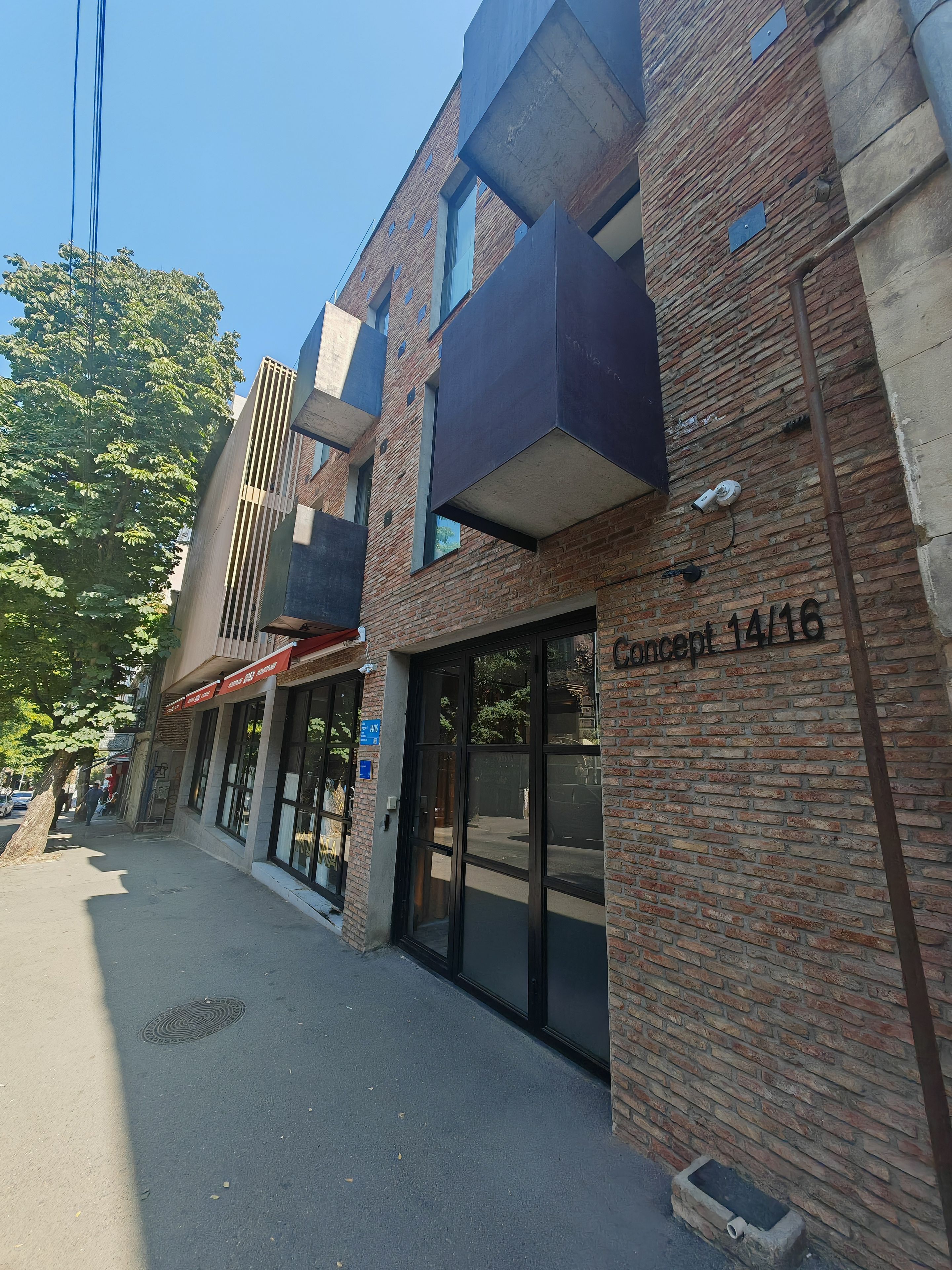 Un bâtiment à la façade en briques, doté de grandes fenêtres et d’une enseigne indiquant l’adresse, bien visible.