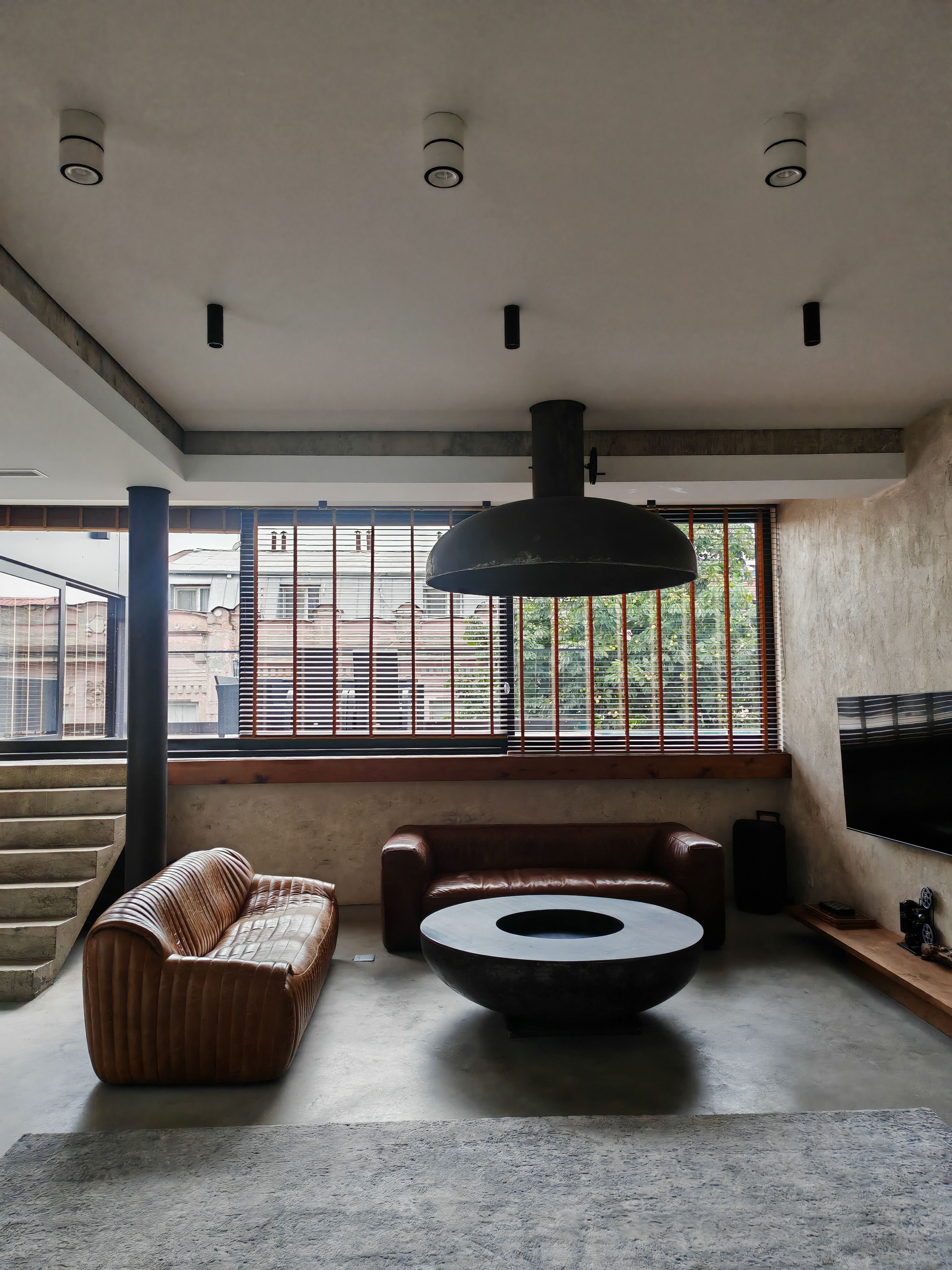 Uma sala de estar moderna com sofá, mesa de centro e uma janela grande com persianas.