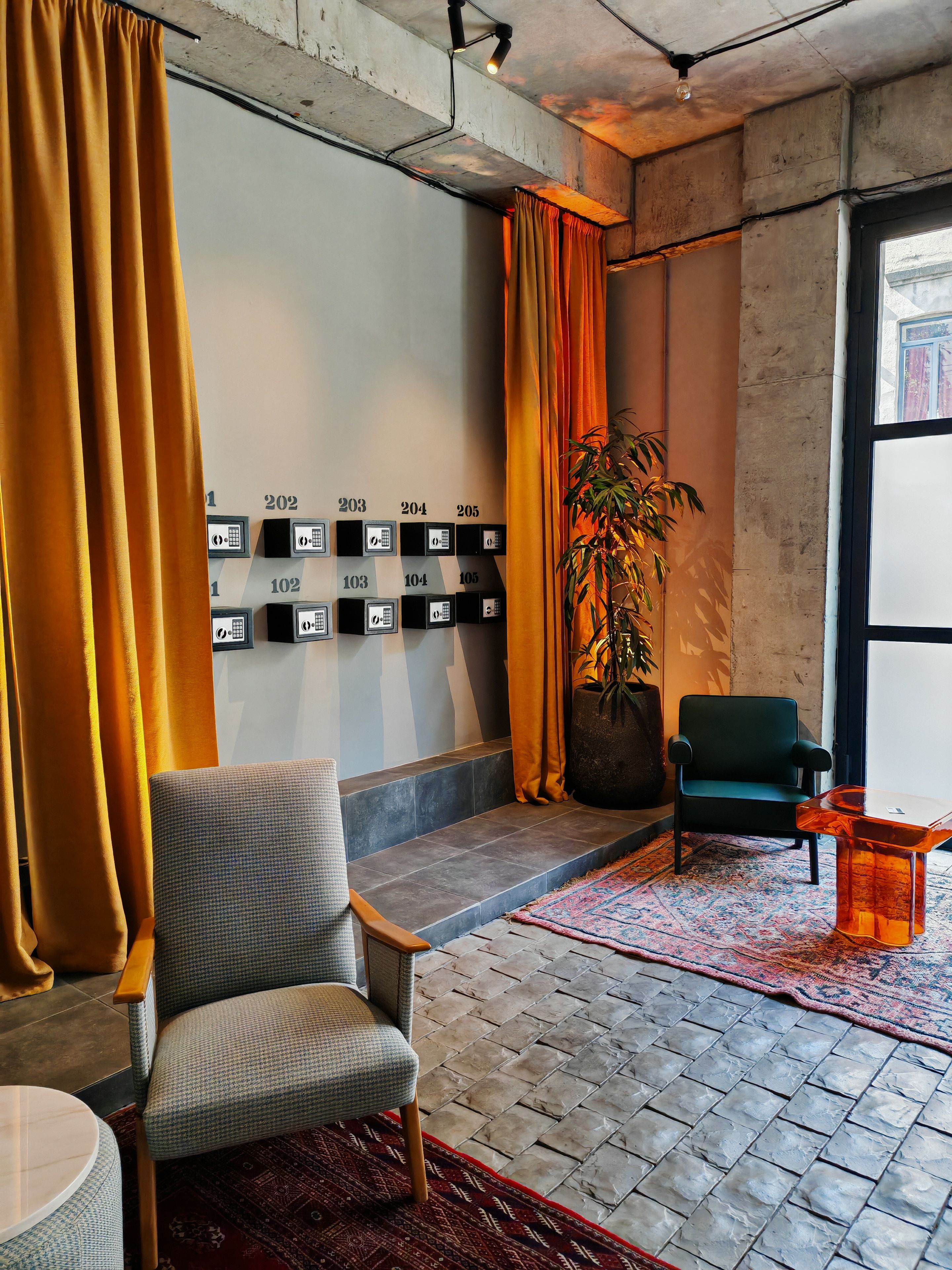 A modern interior with a seating area, a potted plant, and a wall with numbered storage boxes.