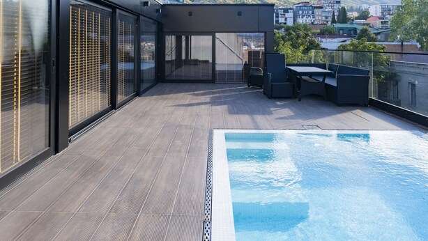 Un espace piscine situé sur le toit, offrant une vue sur une colline et des bâtiments en arrière-plan.