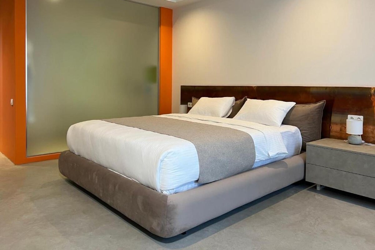 A modern bedroom with a large bed, a nightstand, and a sliding door closet.