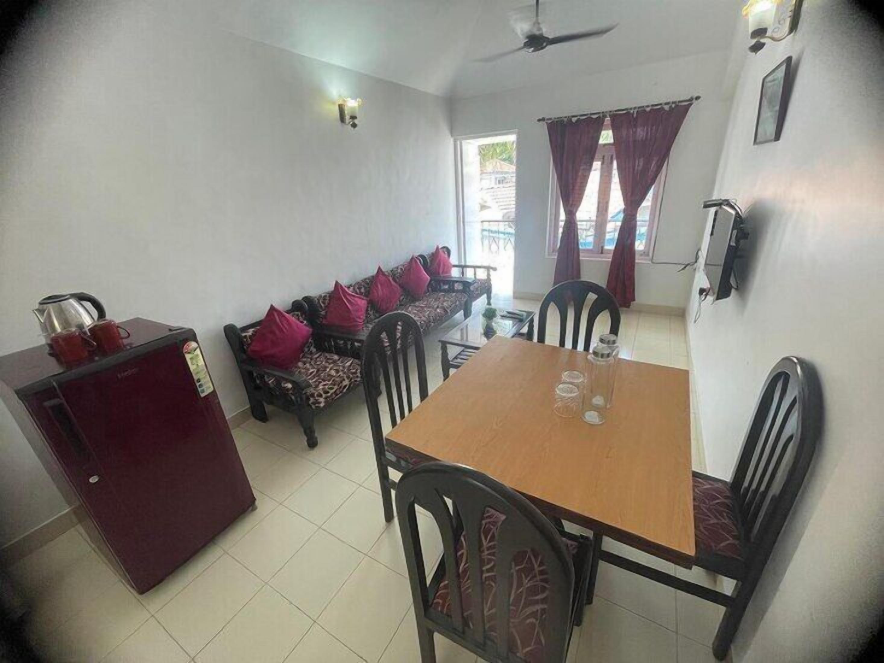 Un espacio habitable compacto con sofá, mesa de comedor, sillas, refrigerador y ventilador de techo.