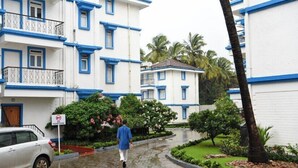 Un edificio residencial con detalles azules y balcones, un camino de entrada mojado y un letrero que indica zona de no estacionamiento.