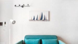 En teal sofa med to puder i et rum med hvid væg.