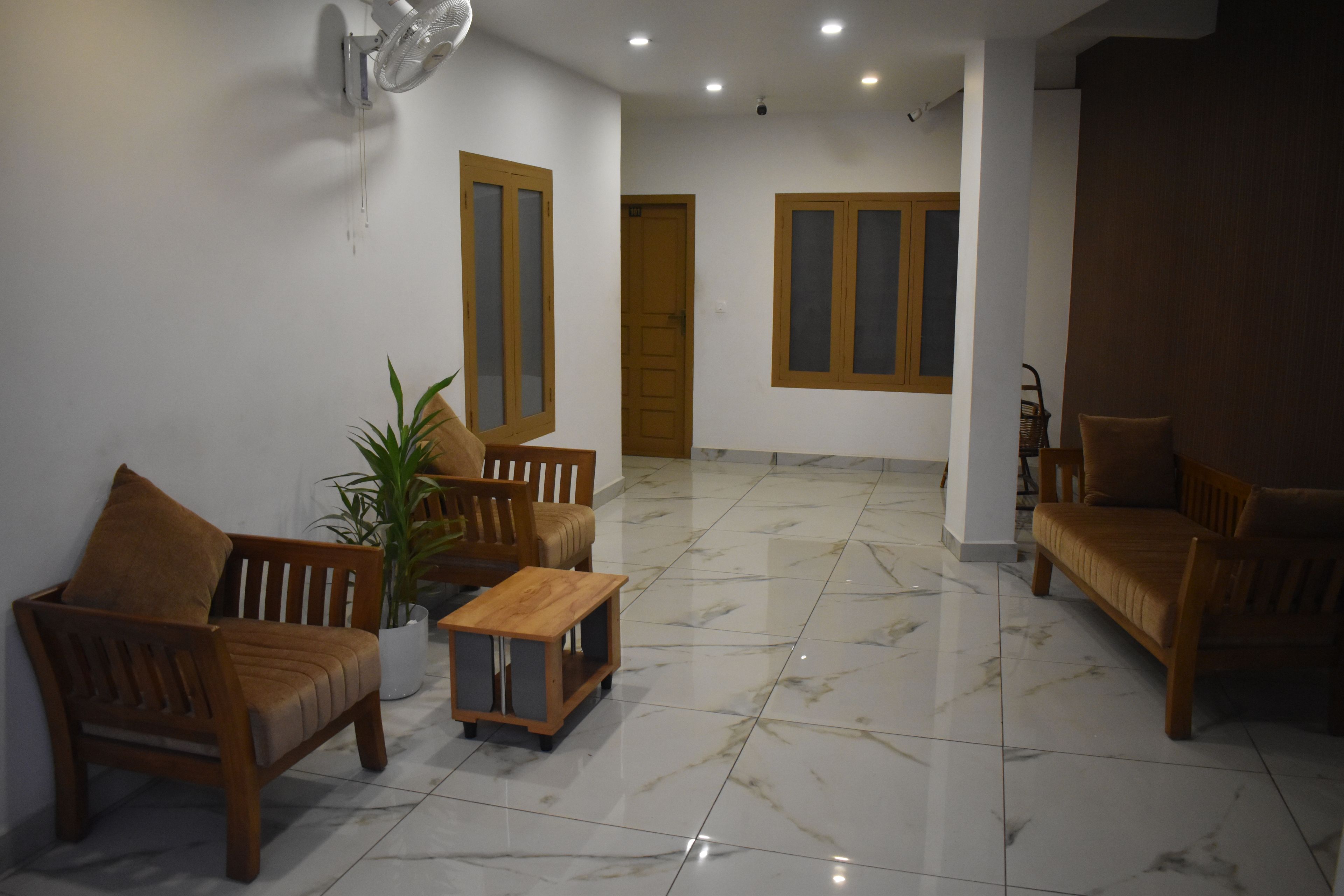 A spacious living area with a marble floor, wooden furniture, and a potted plant.