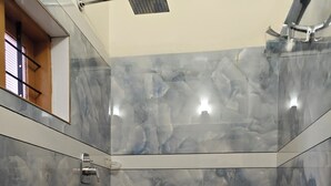 A bathroom with a toilet, a sink, and a shower area with marble tiles. - Aman Residency (Thodupuzha)
