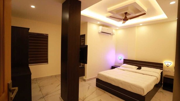 A bedroom with a bed, a ceiling fan, recessed lighting, and a wall-mounted air conditioner. - Aman Residency (Thodupuzha)
