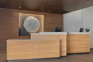 Un mostrador de recepción de diseño moderno, con terminación en madera y una gran decoración mural abstracta.