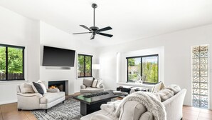A modern living room with a fireplace, two sofas, a coffee table, and a ceiling fan.