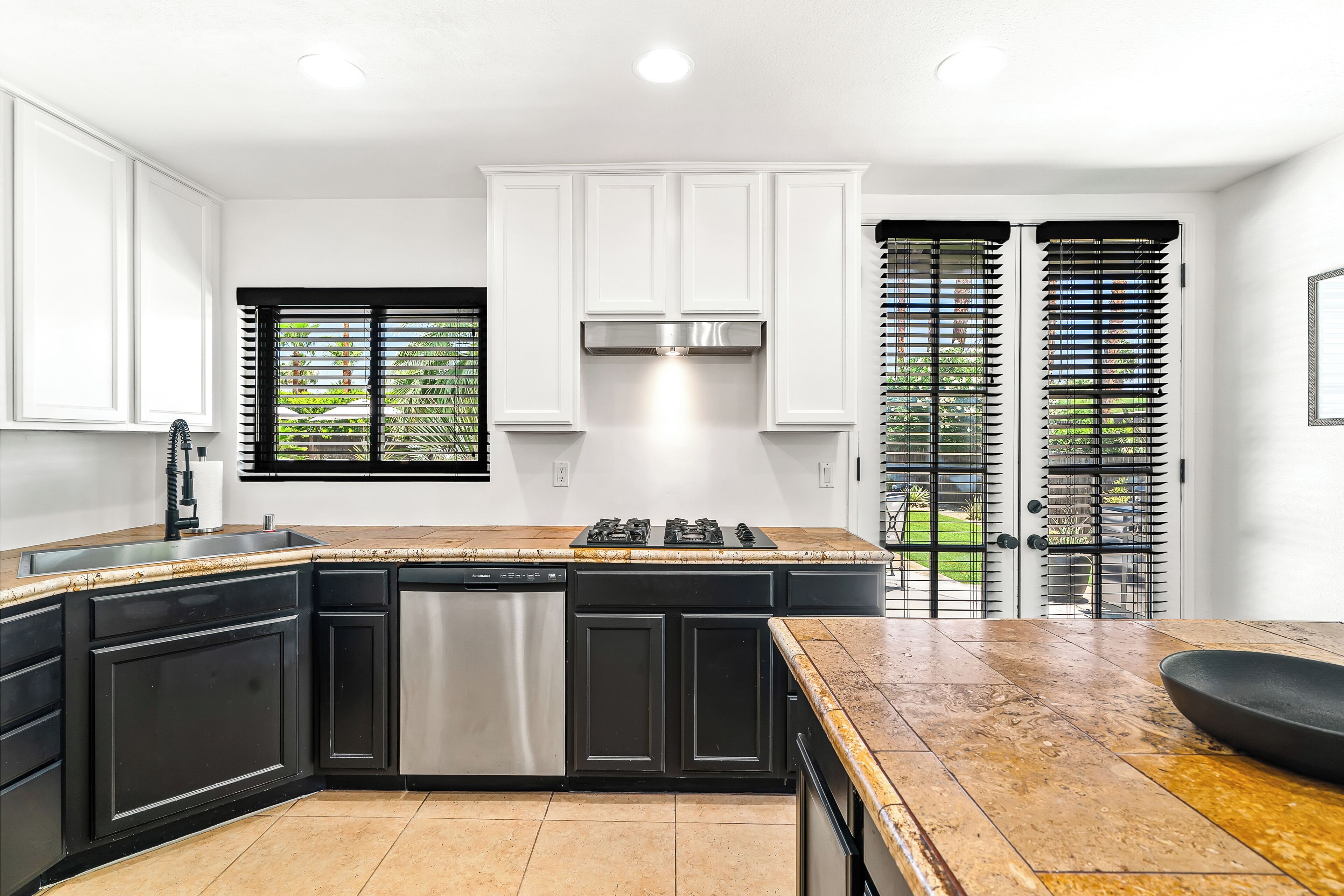 A modern kitchen with a large island, built-in appliances, and a view of the outdoors through the sliding glass doors.