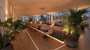A long, well-lit bar area with wooden flooring and multiple seating options, including tables and chairs.