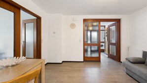 Ein Korridor mit Holzboden, einem grauen Sofa und einem Holztisch mit einem dekorativen Gegenstand.