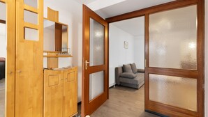 Ein Zimmer mit einem Holzschrank, einer Schiebetür aus Glas und einem grauen Sofa.