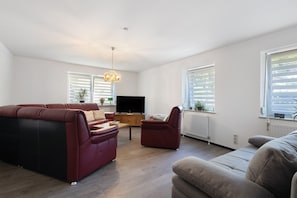 A living room with a red sofa, a beige sofa, a wooden coffee table, and a TV. - Apartment 'Ferienwohnung in Bad Berneck' with Shared Terrace and Wi-Fi (Bad Berneck im Fichtelgebirge)