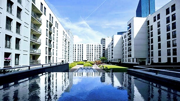 Un bâtiment moderne avec un élément décoratif aquatique réfléchissant au premier plan.