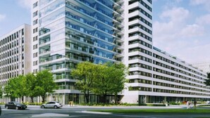 Un immeuble moderne de grande hauteur, doté d’une façade en verre et de nombreux balcons.