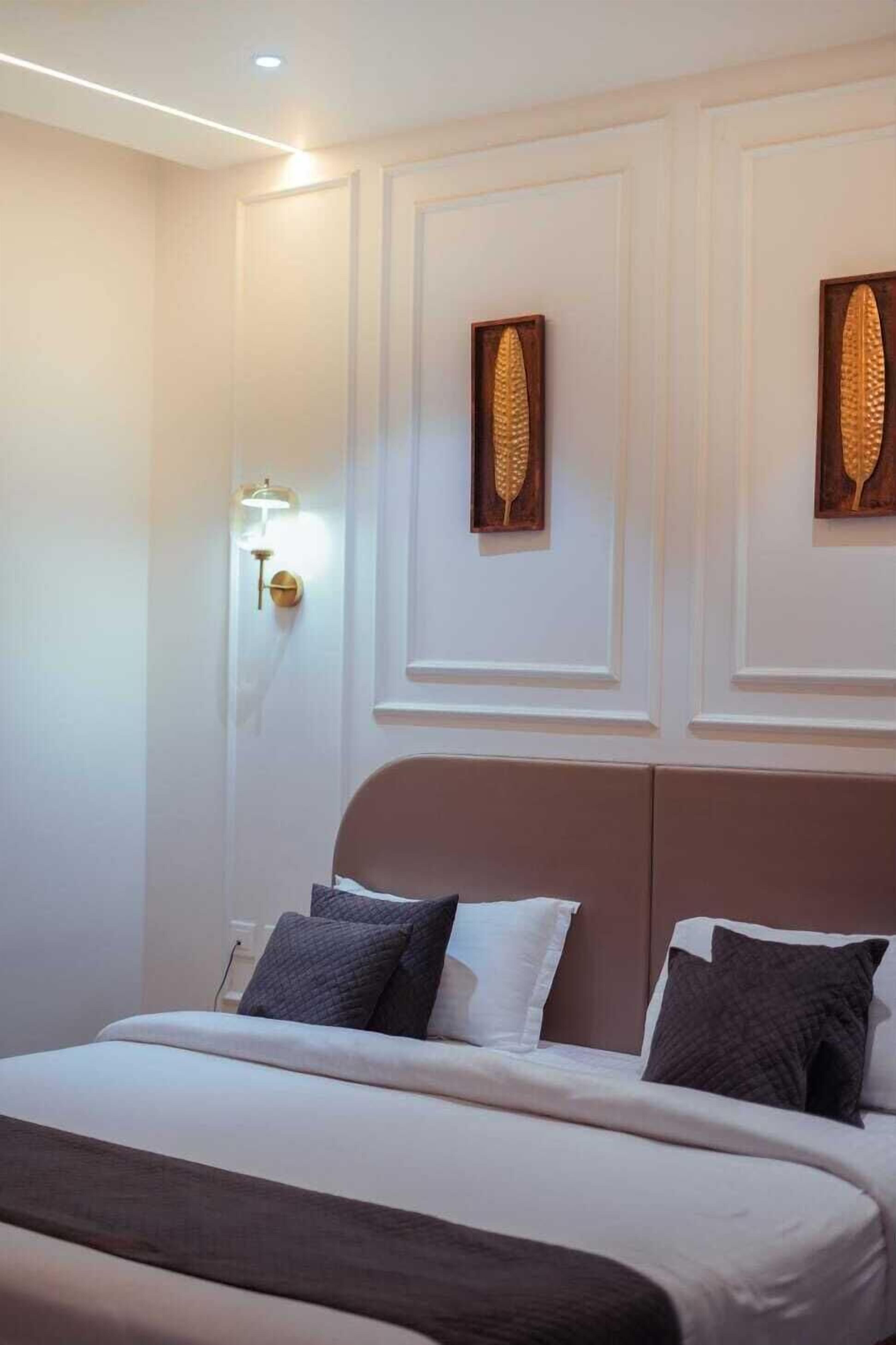 Una habitació d'hotel amb un llit, una làmpada penjada a la paret i dos panells decoratius.