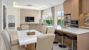 Una cocina moderna con comedor, televisor de pantalla plana y vista a una piscina.