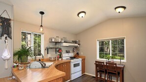 A kitchen with a wooden countertop, white stove, and a dining area with wooden chairs.