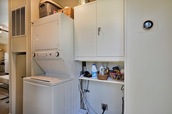 A laundry room with a front-loading washer and dryer, a utility cabinet with shelves, and a ceiling vent. - Wagon Creek Ranch Your Private Retreat in Nature (Mount Shasta)