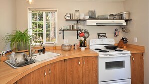 A kitchen with a wooden countertop, white stove, and a window with a view of trees.