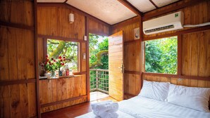 Een houten kamer met een bed, een raam en een airconditioning.