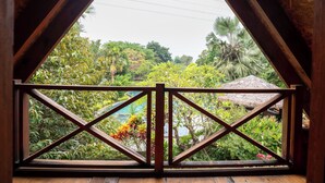 Een houten balkon met uitzicht op een weelderige tuin en een zwembad.