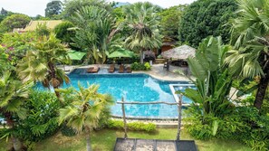 A swimming pool surrounded by lush greenery, with lounge chairs and umbrellas. - GreenField Farmstay Vung Tau (Ho Chi Minh City)