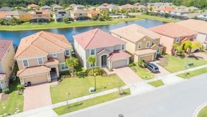 A residential area with houses, a lake, and a road. - 6BR Resort Villa Near Disney | Private Pool 2584 (Kissimmee)