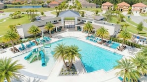 A swimming pool with lounge chairs and palm trees, surrounded by a building with a covered area. - 6BR Resort Villa Near Disney | Private Pool 2584 (Kissimmee)