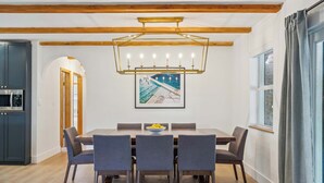 Une salle à manger avec un plafond en bois, un lustre et une œuvre d’art encadrée au-dessus de la table.