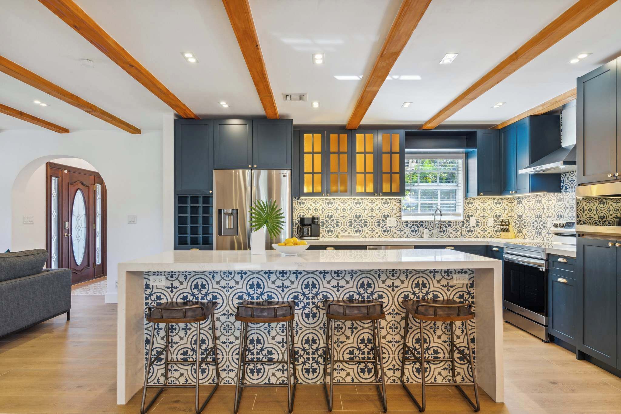Et moderne køkken med en central ø, barstole og en indbygget ovn.