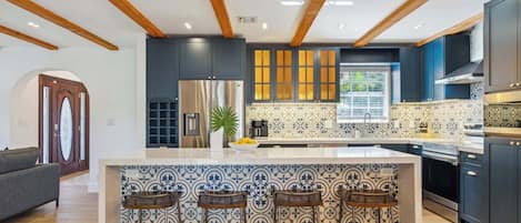 Une cuisine moderne dotée d’un îlot central, de tabourets de bar et d’un four encastré.